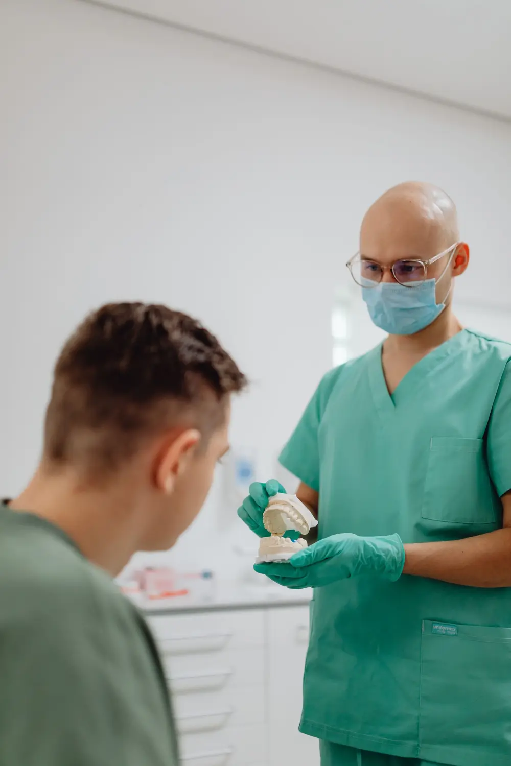 Dental professional in green scrubs with a patient