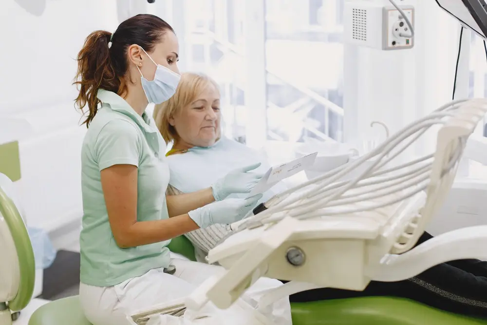 Dental assistant preparing an older patient in a treatment chair